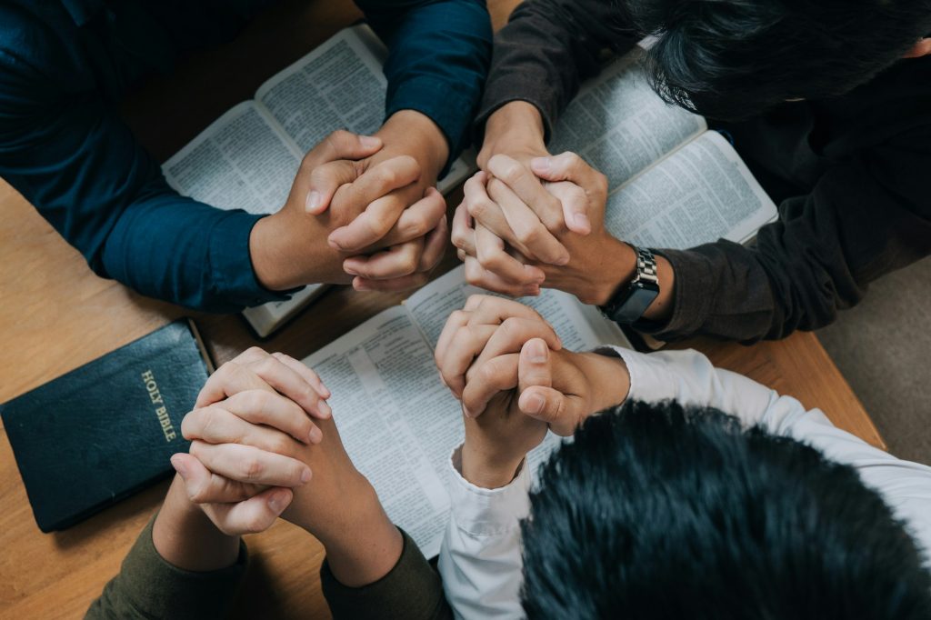 Friends praying together over open Bibles
